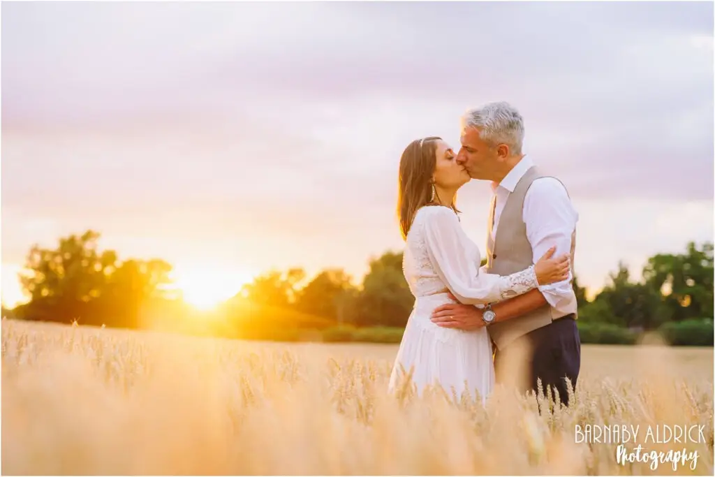 Sunset golden hour cornfield wedding photos at at Yorkshire Wedding Barn near Richmond with a bride in white Bridal Cowgirl boots and a bohemian wedding dress!