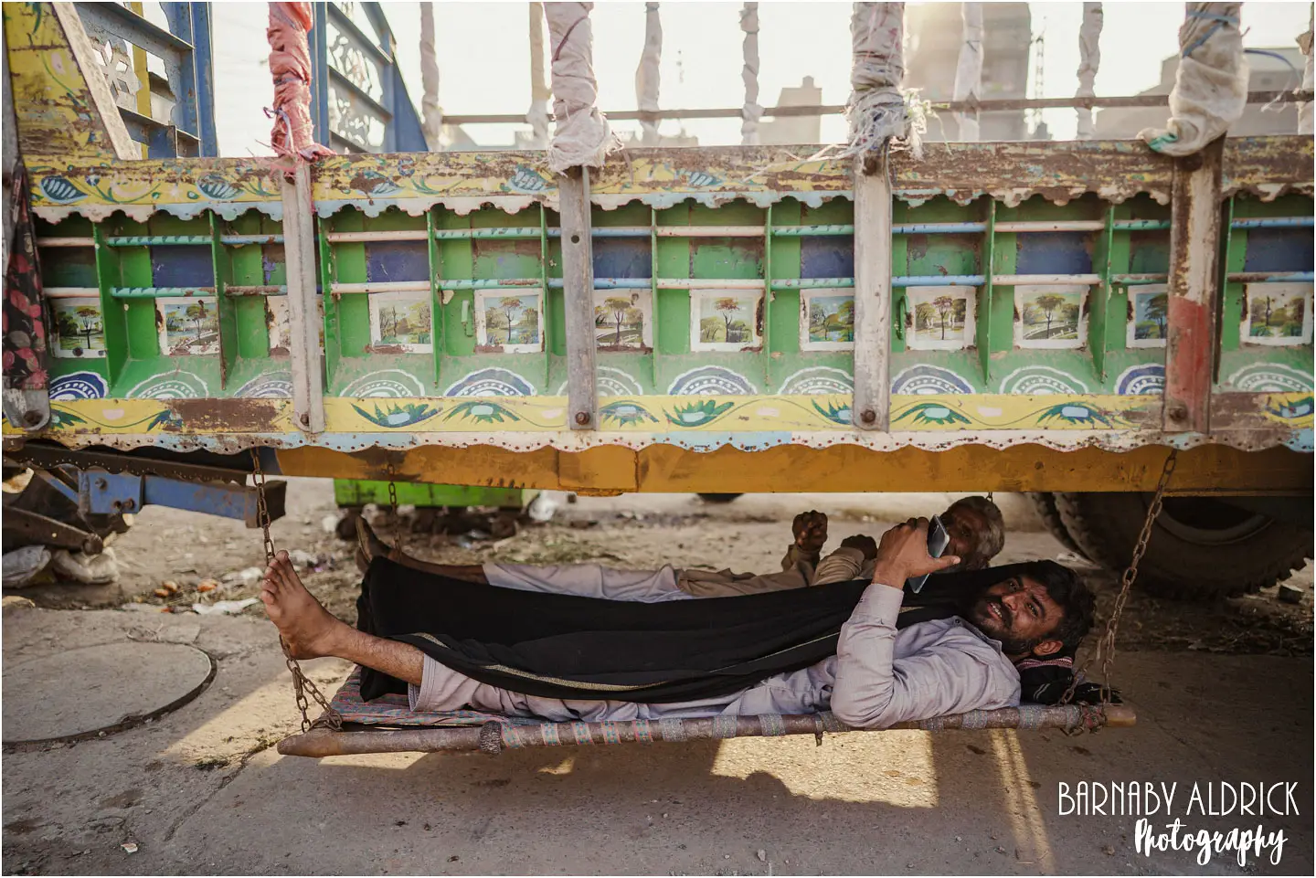 Truck drivers under vehicle hammock in Lahore Pakistan