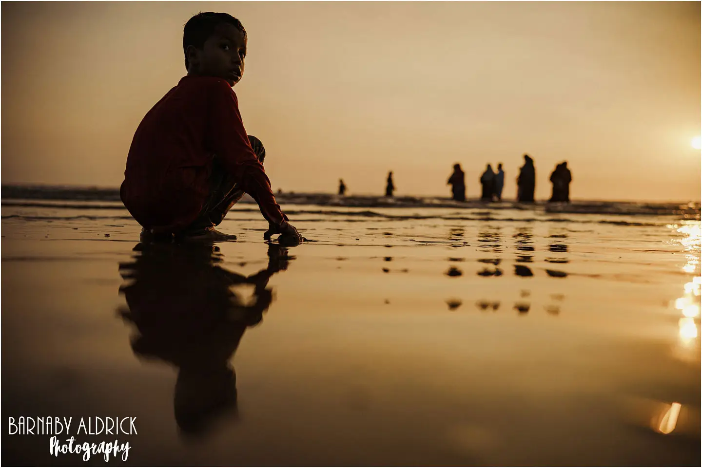 Reflective Sunset scene of a child and family on Clifton Beach Karachi